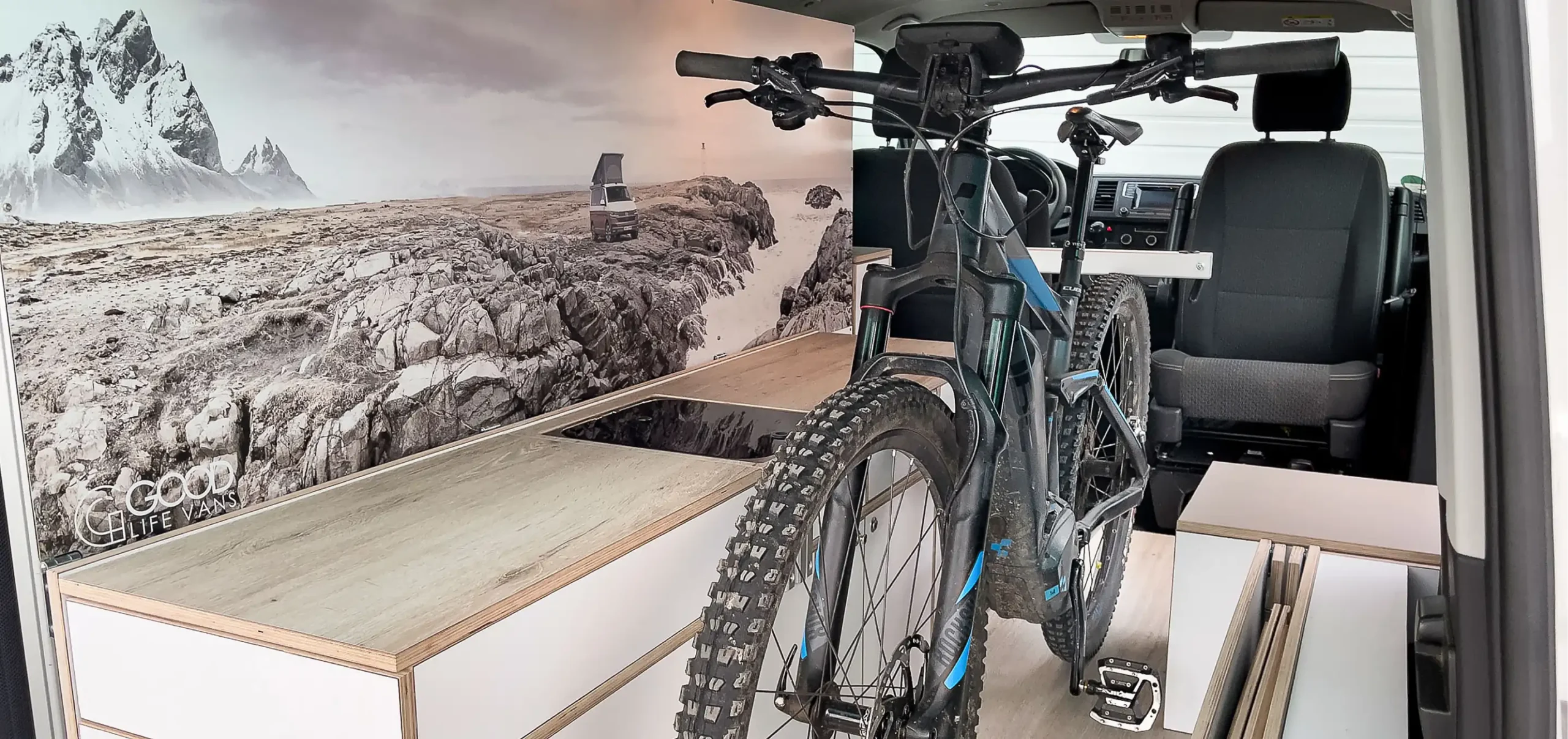 Serienfertigung für Good Life Vans: Tresen mit Küchenplatte aus Massivholz im Fahrzeug, daneben ein Mountainbike