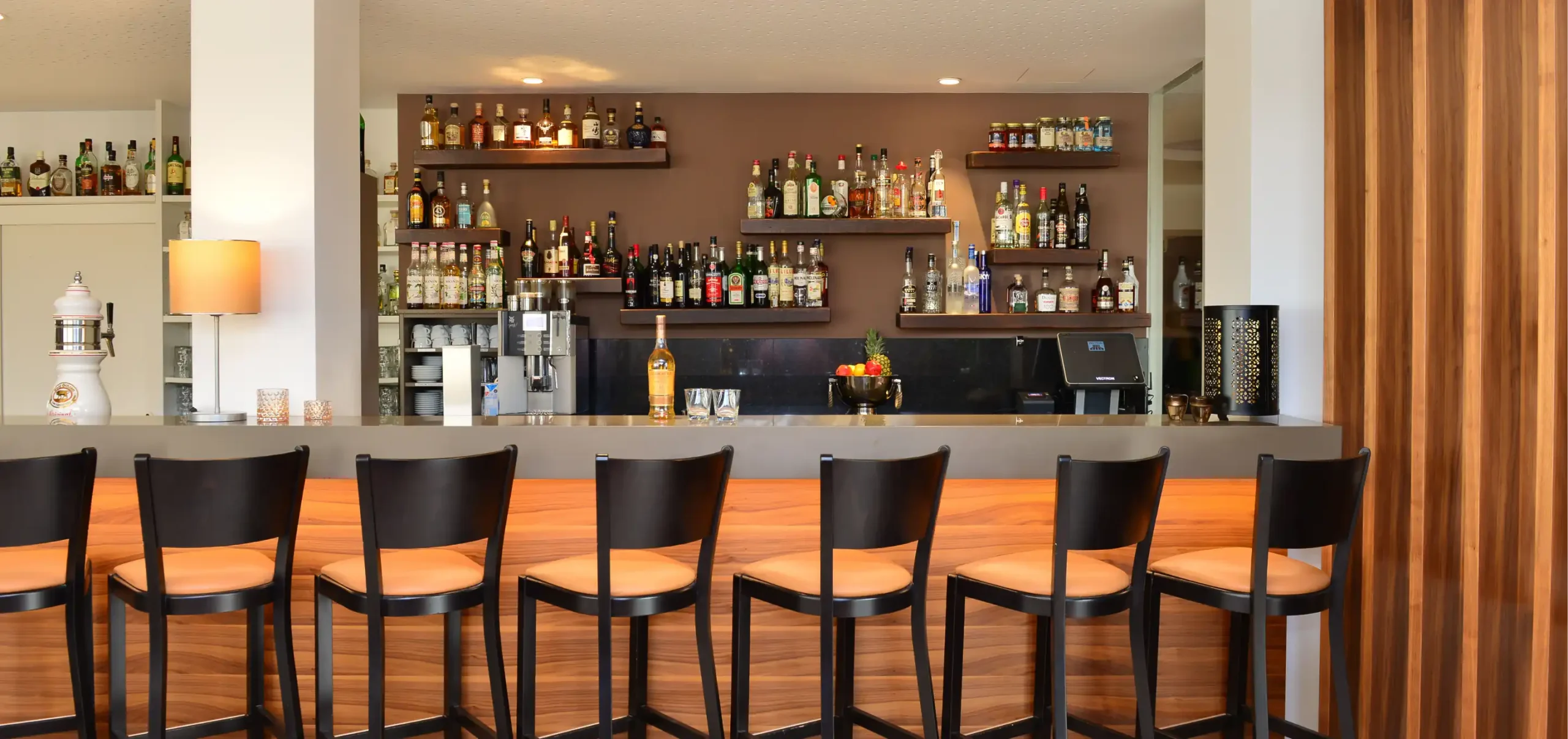 Hotel Lobinger, Barbereich mit Bestuhlung am Tresen, Material Nussbaumfurnier, Flaschenregale