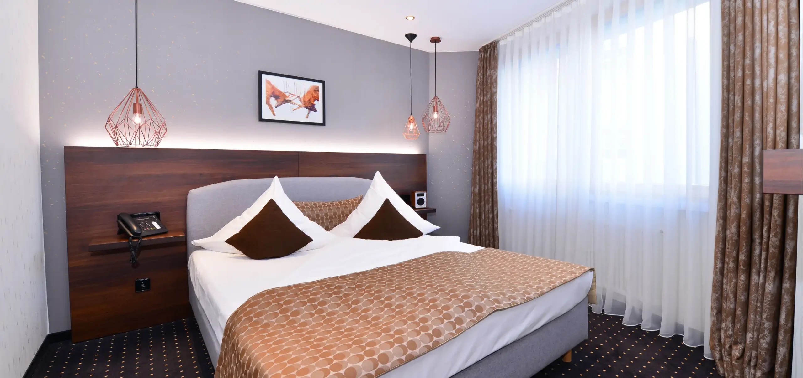 Hotel Lobinger, Gästeizimmer, Ragal mit indirekter Beleuchtung, Gästebett, Nussbaumfurnier, wiederkehrende Elemente aus diesen Material