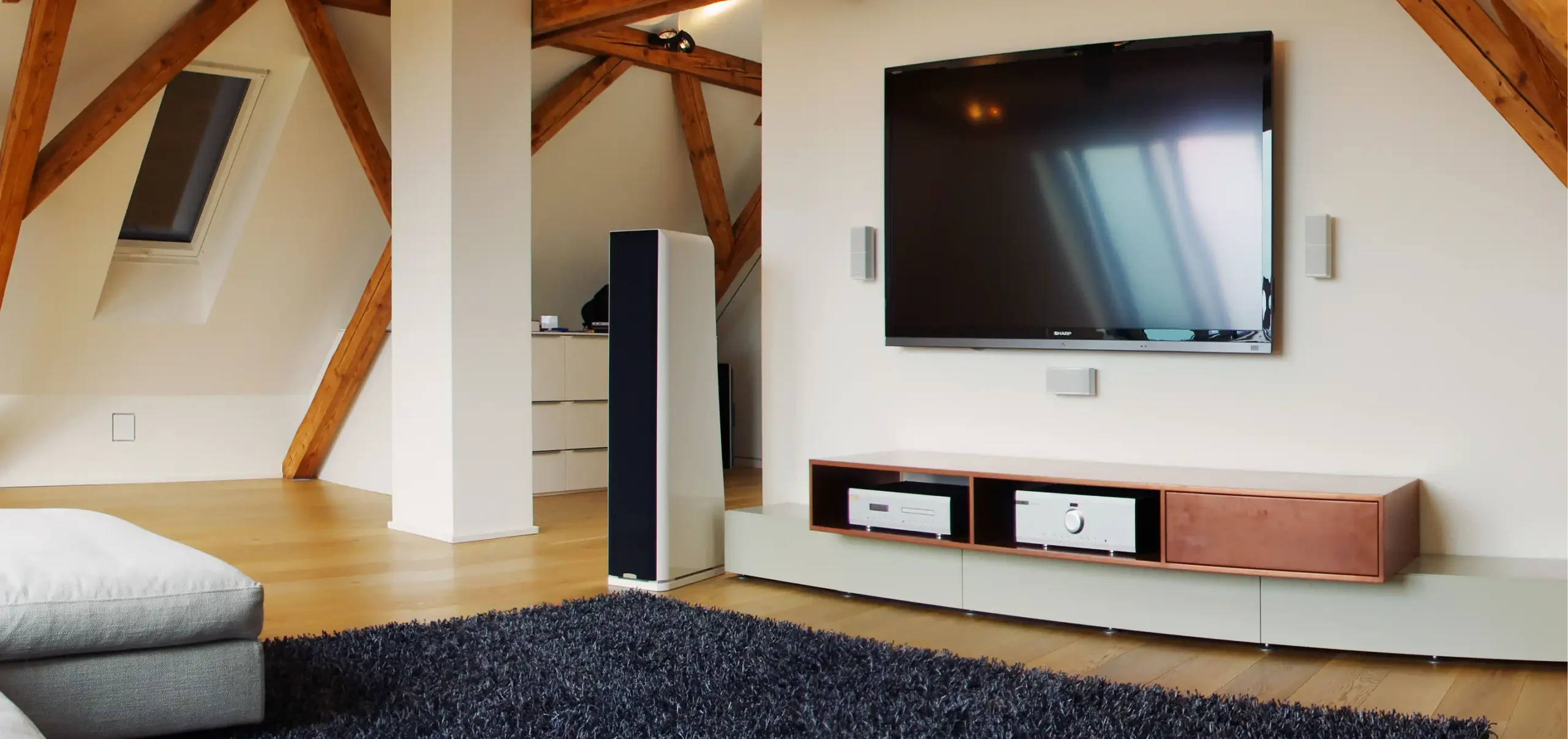 Wohnzimmer im Dachgeschoss, Dachbalken, Fernseher an der Wand mit maßgefertigten Sideboard